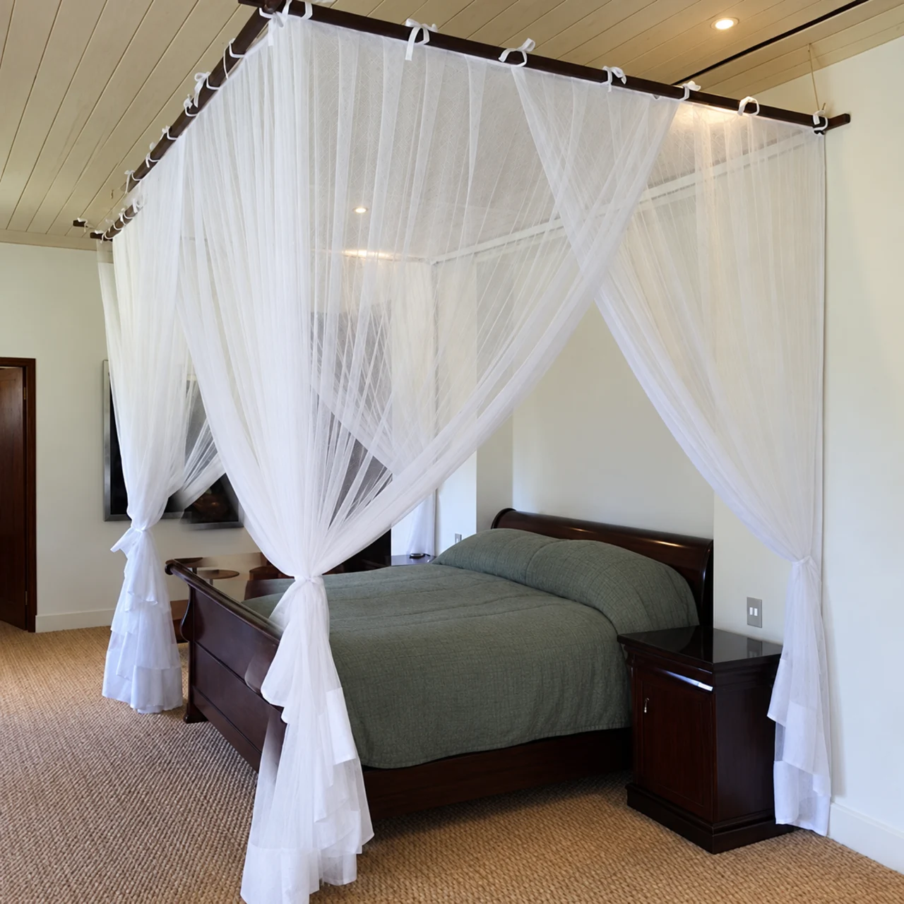 A backless white net suspended from a frame above a round-fronted bed.