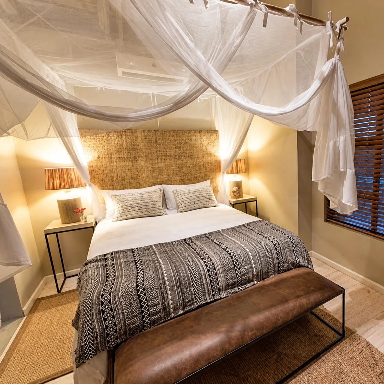A mosquito net gathered into a soft canopy above a bed in a warmly lit bedroom.